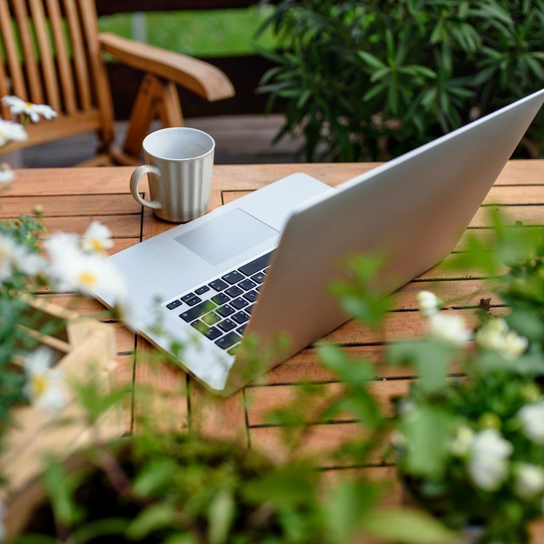 Nurtured Seasons Strategic Consulting Laptop and notebook on wooden table surrounded by greenery — symbolizing reflection, focus, and intentional growth.